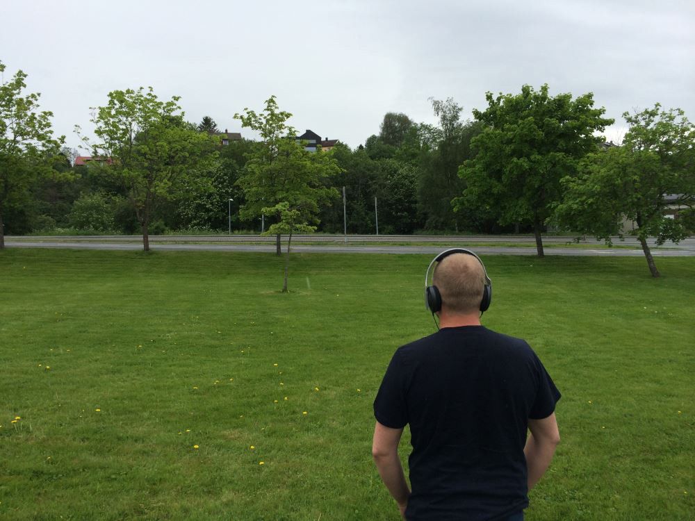 Researcher at SINTEF ICT looking out across a planned road project. Even though there are no cars yet, he can still hear the traffic. Photo: SINTEF ICT.